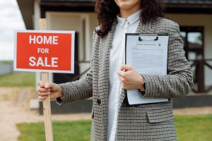 woman holding for sale sign and title insurance policy